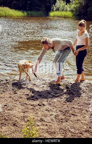 Paar mit Hund am Ufer spielen Stockfoto