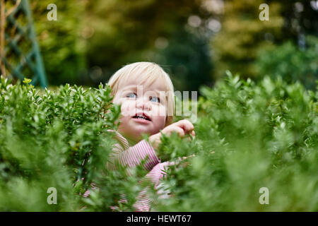 Babymädchen umgeben von Laub wegschauen Stockfoto