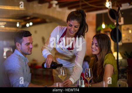 Kellnerin serviert Wein an Kunden im restaurant Stockfoto
