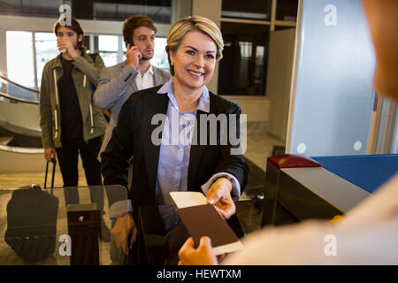 Geschäftsfrau, die Übergabe ihrer Bordkarte an das weibliche Personal am Flughafen-terminal Stockfoto