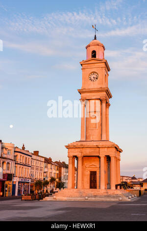 England, Herne Bay. Direkt am Meer, der Stadt Clock Tower, gebaut 1837, denkmalgeschützte Gebäude, in frühen Morgen Sonnenaufgang orange Licht mit Einstellung Mond Stockfoto