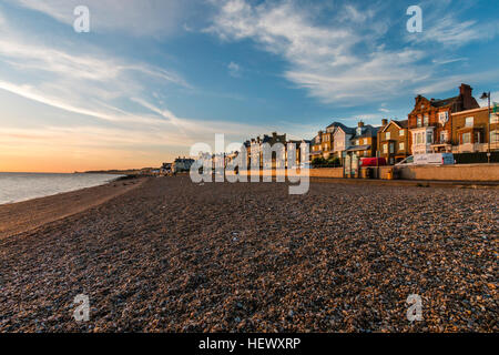 Blick entlang Kiesstrand mit Strandpromenade und der Stadt während den Sonnenaufgang über dem Meer. Abstand, landspitze an Reculver. Stockfoto