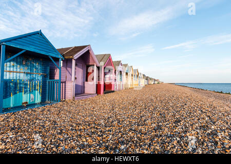 Reihe der Englischen traditionellen Holzhütten am Herne Bay an der Küste von Kent. In verschiedenen hauptsächlich Pastelltönen bemalt. Am frühen Morgen. Strand und Meer. Stockfoto