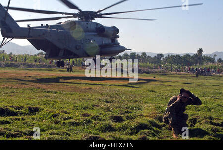 Gunnery Sgt. Joshua Wruble, Firma Gunnery Sergeant, Kilo Unternehmen, Battalion Landing Team, 3. Bataillon, 2. Marine Regiment, 22. Marine Expeditionary Unit, hält Funkkontakt mit der CH-53E Super Stallion von Marine schwere Hubschrauber Geschwader 461 (Reinforced) hebt ab, nachdem sie Nahrung und Wasser während einer Mission zu versorgen, in der Nähe von Leogane, Haiti, Jan. 22 geliefert. Die 22. MEU hat Lieferungen im Bereich um die Opfer des Erdbebens seit, Jan. 19 Hilfe verteilt. Marine Heavy Helicopter Squadron 461 (Reinforced) als es hebt ab, nachdem sie Nahrung und Wasser DVIDS244466 geliefert Stockfoto