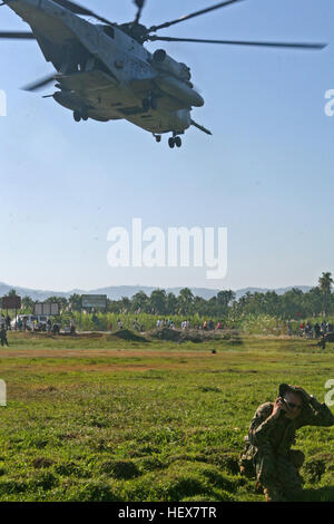 Gunnery Sgt. Joshua Wruble, Firma Gunnery Sergeant, Kilo Unternehmen, Battalion Landing Team, 3. Bataillon, 2. Marine Regiment, 22. Marine Expeditionary Unit, hält Funkkontakt mit der CH-53E Super Stallion von Marine schwere Hubschrauber Geschwader 461 (Reinforced) hebt ab, nachdem sie Nahrung und Wasser während einer Mission zu versorgen, in der Nähe von Leogane, Haiti, Jan. 22 geliefert. Die 22. MEU hat Lieferungen im Bereich um die Opfer des Erdbebens seit, Jan. 19 Hilfe verteilt. Marine Heavy Helicopter Squadron 461 (Reinforced) als es hebt ab, nachdem sie Nahrung und Wasser DVIDS244463 geliefert Stockfoto