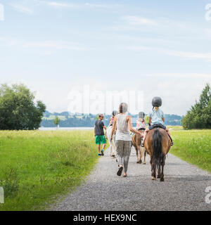 Rückansicht der Eltern führen Kinder auf Pferd, Füssen, Bayern, Deutschland Stockfoto