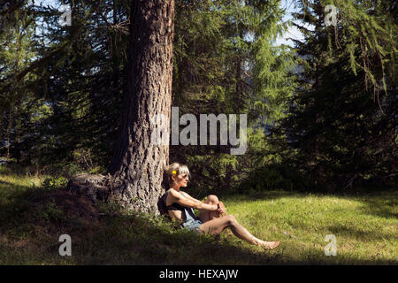 Mitte Erwachsene Frau gelehnt Wald Baum Stamm, Sattelbergalm, Tirol, Österreich Stockfoto