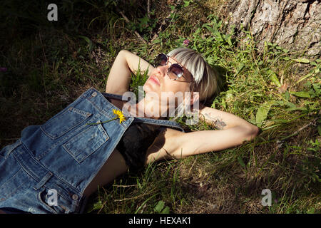 Mitte erwachsenen Frau liegt auf dem Rasen im Sonnenlicht, Sattelbergalm, Tirol, Österreich Stockfoto