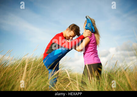 Paar im hohen grass tun stretching-Übungen Stockfoto