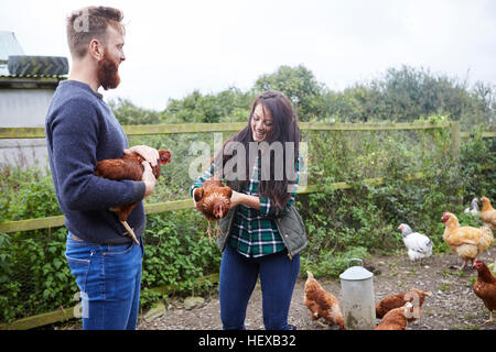 Junges Paar auf der Hühnerfarm halten Hühner Stockfoto