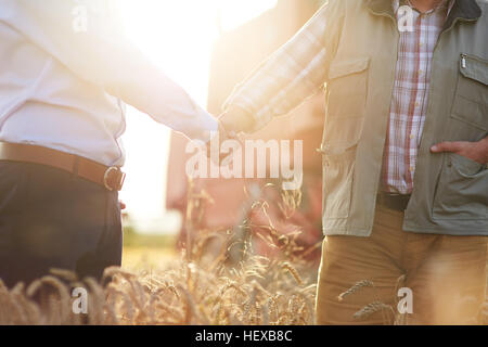 Ansicht der Landwirt und Geschäftsmann im Weizenfeld Händeschütteln beschnitten Stockfoto