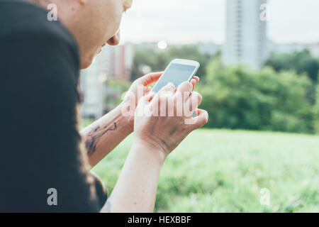 Schuss von Frau auf Rasen mit Smartphone Touchscreen beschnitten Stockfoto