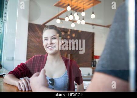 Junge Frau sitzt mit Mann im Café, Lächeln Stockfoto