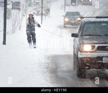 Ein Mann bekommt ein Skilift hinter einem LKW auf einer Straße in einem Winter Schneesturm Schneesturm.  Squamish BC, Kanada Skispaß während eines Schneesturms Winter. Stockfoto