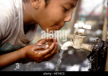 Dhaka, Bangladesch. 24. Dezember 2016. Ein Kind ist Trinkwasser als Eltern Arbeit auf Kohle Feld. Bangladeshi Kohle Feld Arbeit entlädt Kohle in der Nähe der Turag River bei Gabtoli. Arbeiter das Haus verlassen für ein besseres Einkommen bekommen sie nur 7,5$ für 12 Stunden Arbeit. © MD. Mehedi Hasan/Pacific Press/Alamy Live-Nachrichten Stockfoto