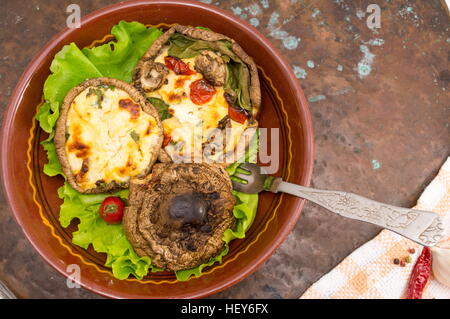 Ei-gefüllte Champignons auf einem braunen Teller mit Cherry-Tomaten Stockfoto