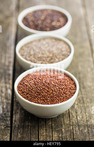 Rote und schwarze Quinoa und Chia Samen in Schüssel auf alten Holztisch. Stockfoto