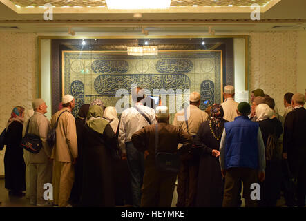 Eine Gruppe von türkischen Besucher aufmerksam betrachten Sie ein altes Stück des Vorhangs die Kaaba in der Heiligen Koran Ausstellung. Medina, Saudi-Arabien. Stockfoto