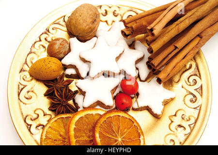 Weihnachtsteller: Zimtstangen, sternförmige Zimt Cookies, Sternanis, getrocknete Orangenscheiben, Hagebutten und Nüssen Stockfoto