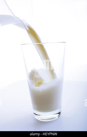 Milch aus einem Krug in ein Glas gegossen wird Stockfoto