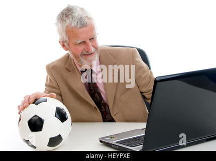 Älteren Geschäftsmann arbeiten am Laptop, Fußball auf seinem Schreibtisch Stockfoto