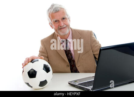 Älteren Geschäftsmann arbeiten am Laptop, Fußball auf seinem Schreibtisch Stockfoto