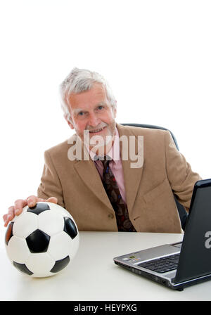 Älteren Geschäftsmann arbeiten am Laptop, Fußball auf seinem Schreibtisch Stockfoto