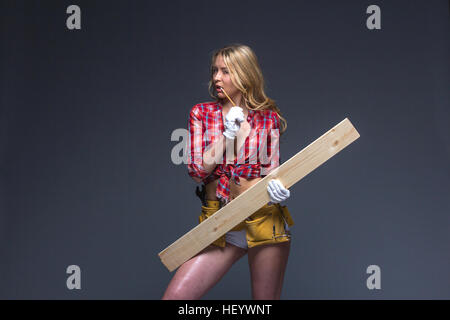 Hübsche Frau Bauarbeiter mit Werkzeug Gürtel und Seil in ihren Händen. Stockfoto