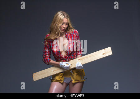 Hübsche Frau Bauarbeiter mit Werkzeug Gürtel und Seil in ihren Händen. Stockfoto