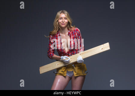 Hübsche Frau Bauarbeiter mit Werkzeug Gürtel und Seil in ihren Händen. Stockfoto