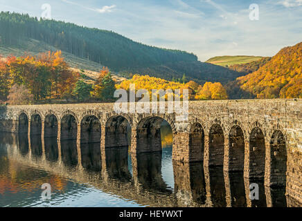 Die Straßenbrücke Garreg Ddu Damm in der Elan-Tal Mid Wales mit Reflexion an einem hellen, sonnigen Herbsttag Stockfoto