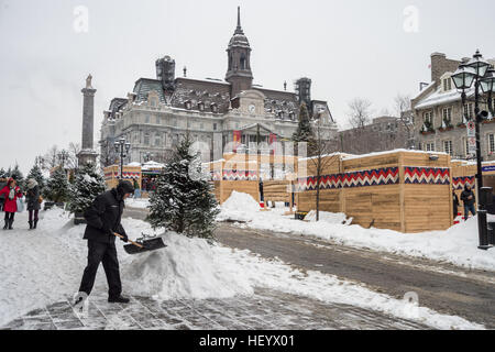 Montreal, CA - 17. Dezember 2016: Mann mit Schneeschaufel reinigt Bürgersteig während Weihnachtsmarkt am Place Jacques Cartier Stockfoto