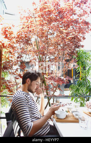 Kaukasischen Mann Essen in Tokyo, Japan Stockfoto