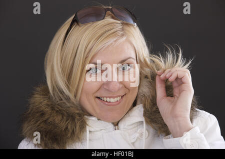 Blonde Frau trägt weiße Pelz-Trim-Mantel Stockfoto