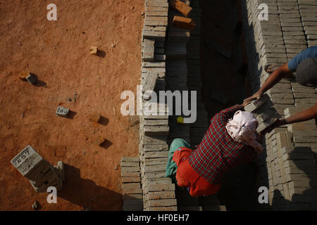 Bhaktapur, Nepal. 27. Dezember 2016. Wanderarbeitnehmer Stapeln rohen Ziegel in einer Ziegelei in Bhaktapur, Nepal auf Dienstag, 27. Dezember 2016 zu brennen. Nepalesischen und indischen saisonale Arbeiter kommen in der Wintersaison an Öfen arbeiten. © Skanda Gautam/ZUMA Draht/Alamy Live-Nachrichten Stockfoto