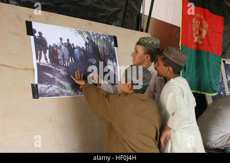 PATROL BASE FULOD, Sangin, Provinz Helmand, Afghanistan - afghanischen jungen sprechen untereinander über ein Plakat zeigt einen abgeschlossenen Kanal-Projekt in Gorgai Dorf am ein Asura statt vom Bezirk Finanzen und Administration Officer, der Bezirk Kommunikation Berater und der kommandierende Offizier der lokalen afghanischen Nationalarmee Unternehmen in der Nähe von Patrol Base Fulod, Juli 26. GIRoA, halten ANA Shura Verbindung mit Sangin Dorf 110726-M-VI905-054 Stockfoto