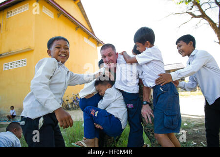 111212-M-IS773-031 REAM NAVAL BASE, Kambodscha (12. Dezember 2011) Kinder klettern auf Major Brad Ward an einer Grundschule. Ward dient als erster Offizier für die 11. Marine Expeditionary Unit (MEU 11.) Bekämpfung Logistik Element, Bekämpfung Logistik-Bataillon 11.  Marines, 11. MEU zugeordnet sind in den USA operierende 7. Flotte Aufgabengebiet als Bestandteil der Makin Island bereit.  (Foto: U.S. Marine Corps CPL. Tommy Huynh) US Navy 111212-M-IS773-031 Kinder klettern auf Major Brad Ward an einer Grundschule Stockfoto