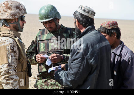 Ein Afghan National Army-Soldat mit Tolay Militärpolizei, 1. Brigade, sammelt 215. Korps Informationen von lokalen Afghanen während seiner Kameraden Suche ihr Fahrzeug während einer Air Interdiction mission mit US-Marines von Regimental Combat Team 5 Schulungsteam hier eingebettet 8. Februar. Afghanische Soldaten durchsuchten verdächtige Fahrzeuge und Personen für Drogen, Waffen und improvisierte explosive Gerätekomponenten während dieses Vorgangs in der dünn besiedelten Wüstenregion südlich von Mardscha Bezirk, westlich des Flusses Helmand. Afghanische Soldaten Interdikt Aufständischen Aktivität vom Himmel 1202 Stockfoto