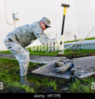 Ein leitender Flieger der 116th Civil Engineering Squadron, Georgia Air National Guard, benutzt einen Vorschlaghammer, um Beton zu entfernen, während er ein Problem mit der Entwässerung von Regenwasser auf der Robins Air Force Base, Georgia, am 13. April 2013 korrigiert. Die Arbeit bietet praktische Schulungen für Wachmänner während eines Trainingswochenendes. Stockfoto
