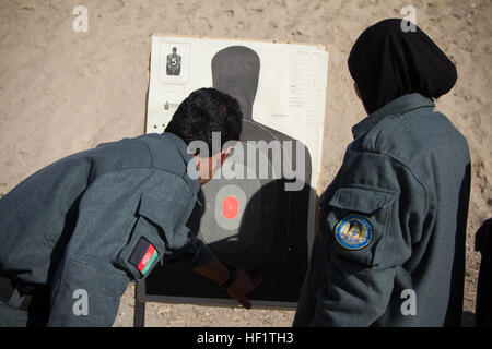 Eine afghanische Nationalpolizei Bereich Sicherheit untersucht einen weiblichen ANP Rekruten Ziel nach Rollout Waffen Qualifikation, 8. Dezember 2013, bei Regional Training Center - Kandahar, Afghanistan. Die 21 Rekruten sind die erste Allfrau Klasse jemals die ANP grundlegende Streifenpolizist Kurs im Süden Afghanistans zu besuchen. (US Armee-Foto von CPL. Mariah beste) Neue Ära der afghanischen nationalen Sicherheitskräfte bereit für die Herausforderung 131208-Z-TF878-878 Stockfoto