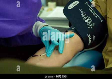 Ein Techniker mit dem Armed Services Blut Programm fügt eine Nadel in eine Marine Arm während der 2. Marine Logistics Group Blut Fahrt an Bord Camp Lejeune, North Carolina, 14. März 2014. Freiwillige spendete ein Pint Blut, die bis zu drei Leben retten kann. (Foto: U.S. Marine Corps Lance Cpl. Shawn Valosin) Blutspenden, Leben retten, spendet 2. MLG 140314-M-IU187-007 Stockfoto