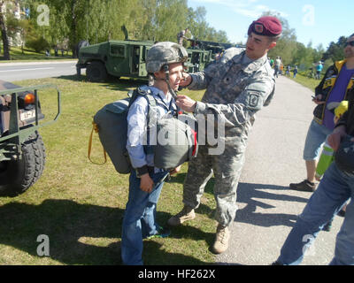 SPC. Anthony Crisci vom 1. Bataillon, 503. Infanterieregiment, 173rd Airborne Brigade, hilft einen lettische jungen in einem t-11-Fallschirm 17. Mai 2014, bei einem Festival in Adazi, Lettland. Die Fallschirmjäger angezeigt US Army Fahrzeuge und Ausrüstungen für die Bewohner ihrer Gastgeber-Stadt; 150 Fallschirmjäger, gehören derzeit Adazi Trainingsbereich als Bestandteil einer außerplanmäßigen Übung NATO Entschlossenheit zu demonstrieren. (Foto: 1. Lt. Daniel Oesterheld US Army) Beteiligung der USA in Adazi Festival 140517-Z-DO999-001 Stockfoto