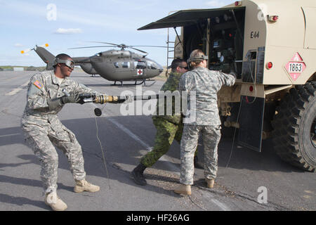Colorado Army National Guard Spc. Nicole Ziemer und Spc. Davionn Johnson, beide Fuelers für das 2. Bataillon, 135. General Support Aviation und kanadischen Streitkräfte CPL. Jose Pinto, ein Fueler für die JTFSC stellt einen Schlauch mit einem Hubschrauber UH-72 Lakota als Teil der Übung Maple lösen im kanadischen Manöver Training Center in Wainwright, Alberta, 20. Mai 2014 zu tanken. Oberste Führung besucht der kanadischen Manöver Training Center in Wainwright, Alberta, während Colorado Army National Guard Luftfahrt Ressourcen an Übung Maple lösen 2014 (EXMR14) vom 5. Mai bis 1. Juni 2014. Stockfoto