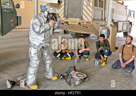 LCpl Stefan Swanson ein Flugzeug-Rettung und Brandbekämpfung-Spezialist mit Marine Wing Support Squadron-274 (MWSS-274), veranschaulicht das setzen auf ein Flammschutzmittel Anzug für Afghan National Army (ANA) Soldaten mit dem 215. Korps, Crash-Fire Rescue Team an Bord Camp Bastion, Provinz Helmand, Afghanistan, 5. Juni 2014. Der Umsatz der Bastion Flugplatz vor ihrer Umschichtung aus der Provinz Helmand bereiten Koalition Soldat innen der ANA. (Offizielle U.S. Marine Corps Foto von CPL James D. Pauly, Marine Expeditionary Brigade Afghanistan/freigegeben) Absturz-Feuerwehr 140605-M-OM358-1 Stockfoto