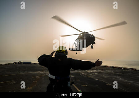 Petty Officer Ian Walker, ein Deck Hand auf die RFA Cardigan Bay, Royal Fleet Auxiliary, britische königliche Marine, gibt das Signal zum abheben, ein UH-60 medizinische Evakuierung Black Hawk von Piloten geflogen vom 1. Bataillon, 214th Air Ambulance, 42. Combat Aviation Brigade (CAB), US-Armee am 8. Juni 2014, irgendwo in den Persischen Golf.  Die Piloten ausgebildet auf Deck Landungen während Übung Spartan Kopis, einen Austausch zwischen der Cardigan Bay und die Black Hawk und AH-64 Apache Elemente der 42. Kabine, New York Army National Guard.    Spartan Kopis war das erste Mal, mit denen amerikanische Apachen eine königliche gearbeitet Stockfoto