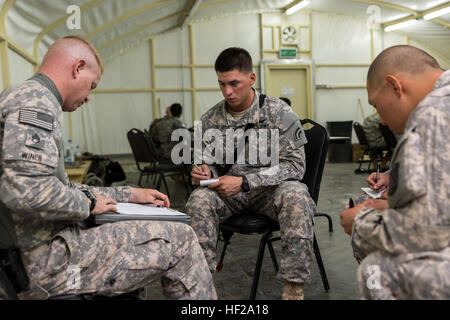 SPC. Robert Diaz, ein Hubschrauber-Werkstatt mit 642nd Aviation Support Battalion, 42. Combat Aviation Brigade, hört eine kurze Mission von Staff Sgt Winer, ein Krieger Leadership Course (WLC) kleine Gruppe Marktführer vor seiner Mannschaft Mission der Nacht des 11. Juli 2014, im Camp Buehring, Kuwait. Die Studenten der US-Army Central Command WLC geplant und geführt Missionen gegen Mock Gegenkräfte über mehrere Fahrspuren der Ausbildung für zwei Nächte, testen ihre Führung und taktische Fähigkeiten zum Abschluss der drei Kurswochen. (New York Army National Guard Foto von Sgt. Harley Jelis/Rele Stockfoto