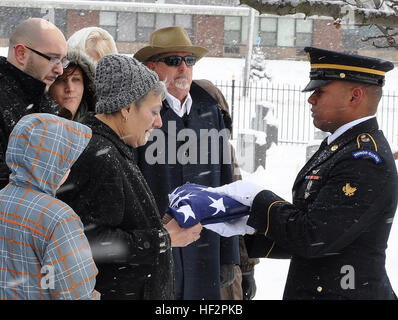 SPC Anthony Bryant, ein Mitglied der New York Army National Guard Ehrengarde, präsentiert eine amerikanische Flagge Michol Smith, die Witwe des Armee-Veteran Charles L. Smith während die Beerdigung am 11. Dezember 2014, auf dem Mount Carmel Cemetery in Amsterdam, N.Y. Bryant, ein Mitglied der Gesellschaft D statt 3. Bataillon 142. Aviation und ein Bewohner des Walkill. New York, ist einer der 124 New York Army National Guard Soldaten ausgebildet, Ehrengarde Aufgaben durchzuführen. (US Army National Guard Foto von Master Sergeant Corine Lombardo/freigegeben) New York Army National Guard durchzuführen 9.600 militärische Begräbnissen in 2014 141211-Z-NU174-0 Stockfoto