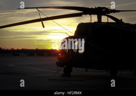 Besatzungen aus Trainingsmissionen zurückgekehrt und UH-60 Black Hawks sind auf dem Flug Linie gesichert, wenn die Sonne beginnt am Ende der Trainingstag auf der McEntire Joint National Guard Base in Eastover, S.C., am 10. Januar 2015 festgelegt. (US Army National Guard Foto von Sgt. Brian Calhoun/freigegeben) SC-Guard-Apachen trainieren, um in der Nacht 150110-Z-ID851-016 tanken Stockfoto