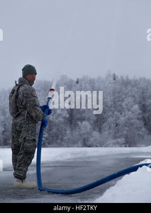 Pvt. Solei, eine horizontale Ingenieur mit der 207. Ingenieur Utility Ablösung, Alaska Army National Guard, sprüht einen frischen Anstrich von Wasser für den Bau einer Eisbrücke während des Trainings das Gerät am Walden-See-Jan. 24. Eis-Brücke-Bau-Training ist wichtig für Alaskas Soldaten zur Vorbereitung einer Naturkatastrophe Hilfe und arktische Kriegsführung. (US Army National Guard Foto von Sgt. Marisa Lindsay) Alaska Army National Guard baut Brücken E280A6 Eis 150125-Z-QK839-445 Stockfoto