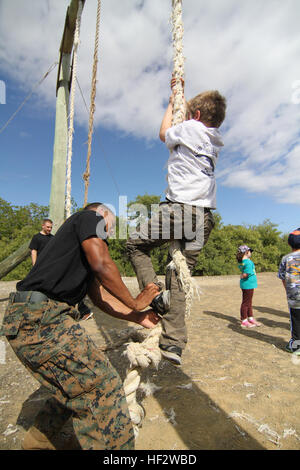 Ein Pfadfinder mit Cub Scout Pack 3401 in Guantanamo Bay auf Kuba erhält Seilklettern Anweisungen aus eine Marine mit Marine Corps Forces Sicherheitsfirma bei den Pfadfindern Pack Marine Hill Jan. 31 abholen. (Foto: US-Armee Sgt. Rick Hoppe / veröffentlicht) Wölflinge, Marines Fähigkeiten 150131-Z-WK979-453 Stockfoto